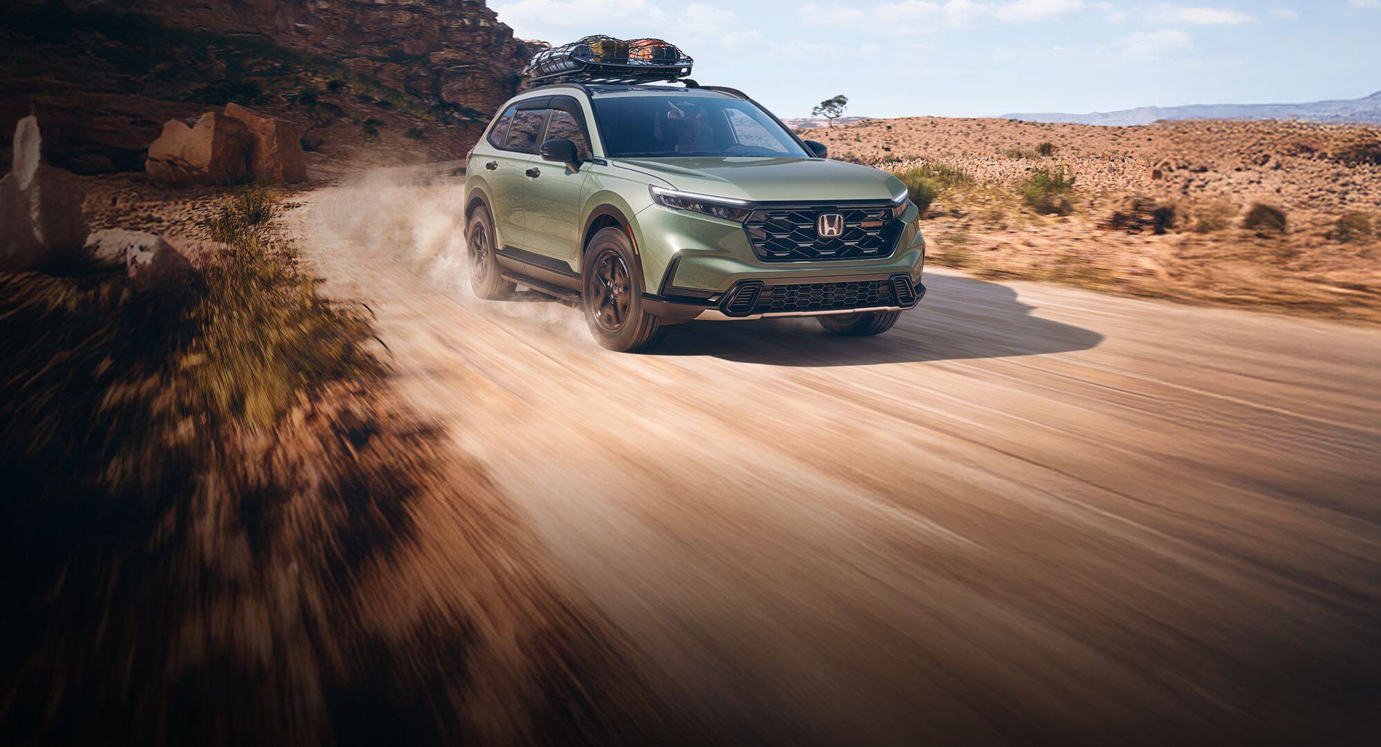 2026 Honda CR-V TrailSport in Ash Green Metallic, 3/4 passenger front of vehicle driving on a dirt road through desert national park landscape